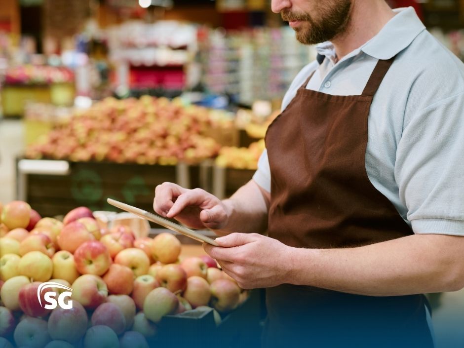 BlogSGSistemas35 Atendente de mercado usando tablet em seção de frutas