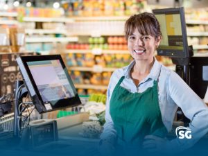 Atendente de supermercado sorrindo na fila do caixa