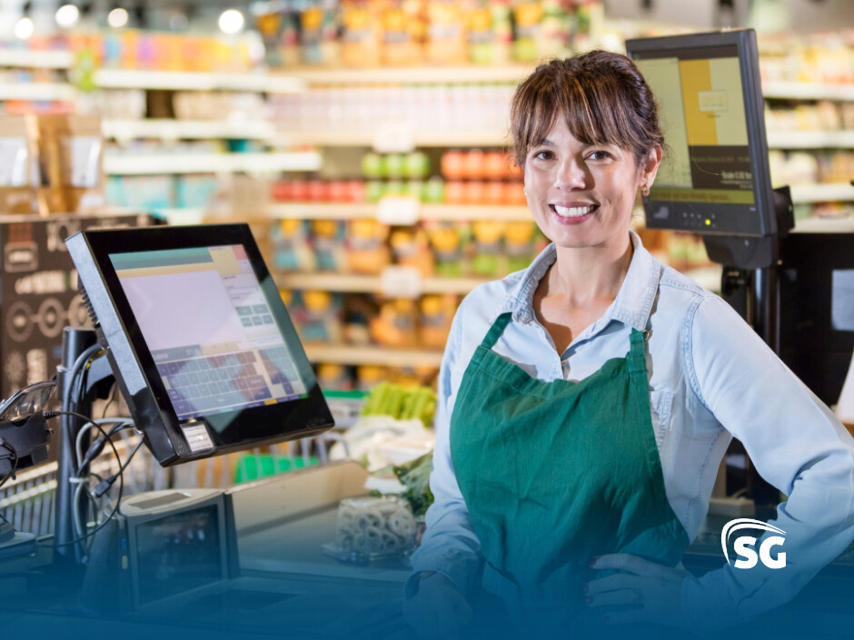 Atendente de supermercado sorrindo na fila do caixa