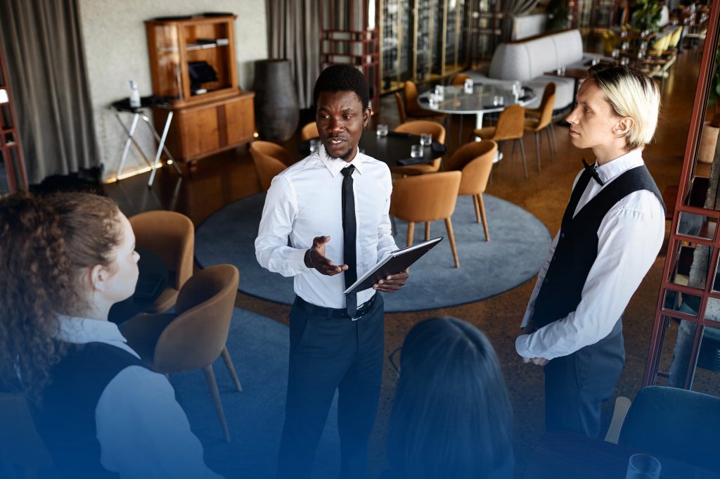 DRIVETHRU8 Homem em traje conversando com equipe de garçons.