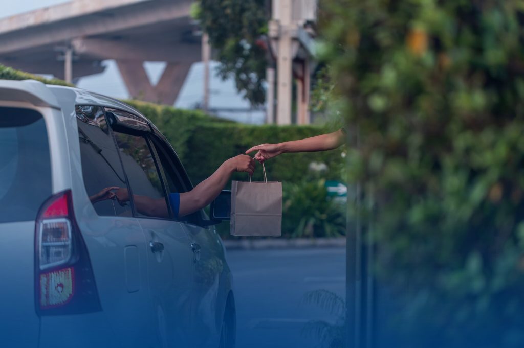 903 DRIVETHRU10 Entregador passando pacote para cliente no carro.