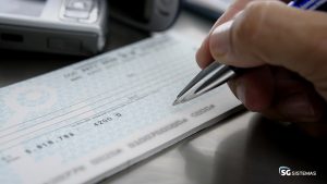 Pessoa preenchendo cheque com caneta